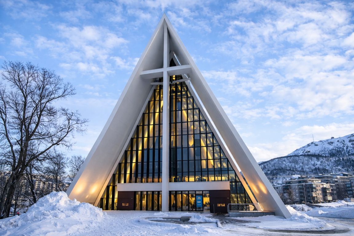 The Arctic Cathedral in Tromsø during a Tromso Norway Tours guided experience, displaying the dramatic A-frame architecture and glowing interior at dusk